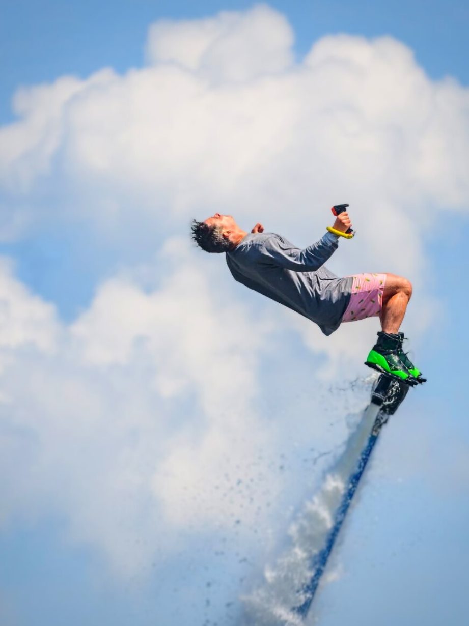 Flyboarder mid trick leaning back against the clouds