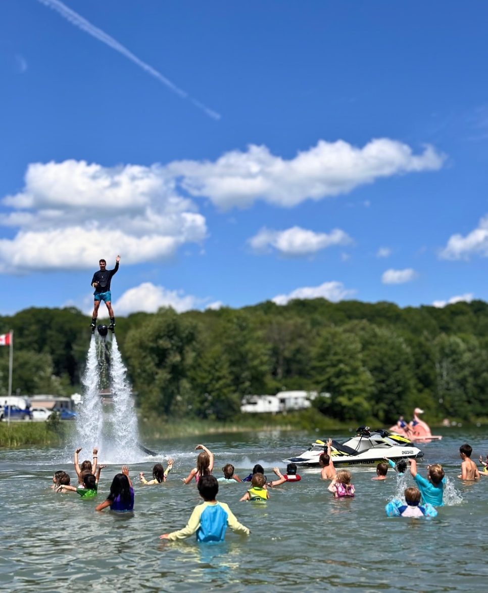 Performer flying above a group of kids cheering in the water