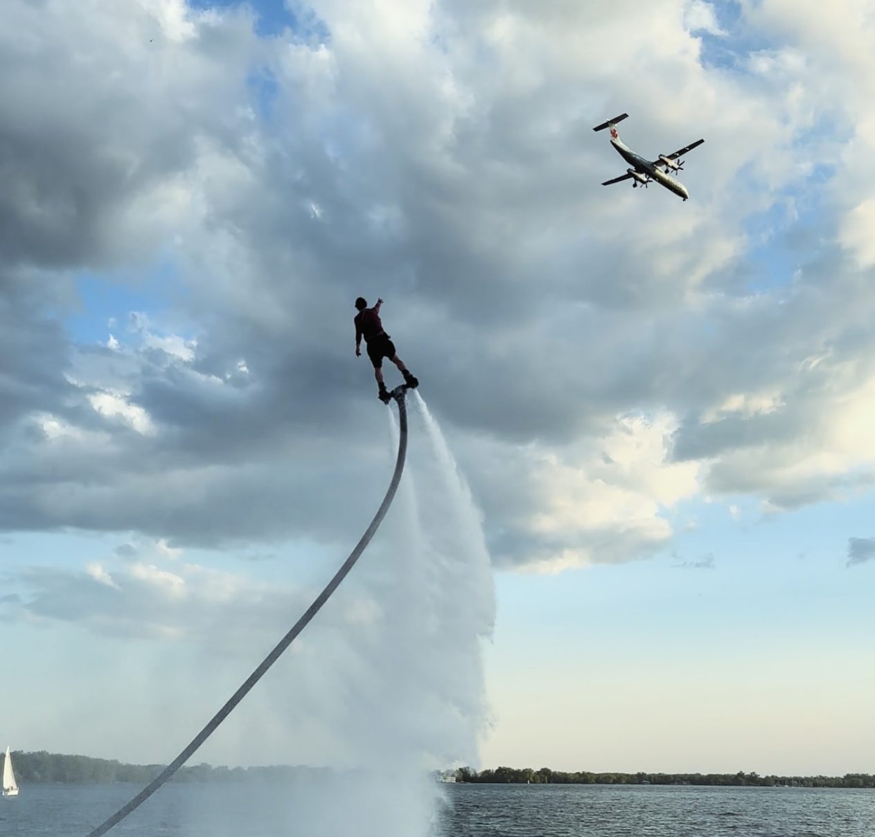 Flyboarder high in the sky as a passenger plane passes behind