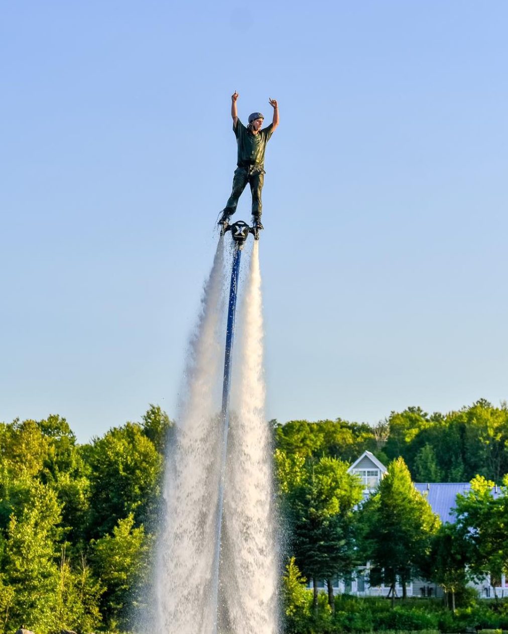 Flyboarder standing tall on a jet of water with arms raised