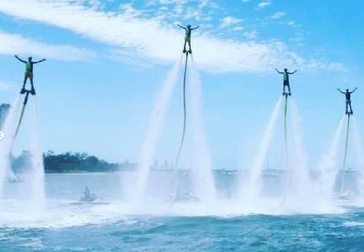 Four flyboarders flying in formation over the lake in daylight
